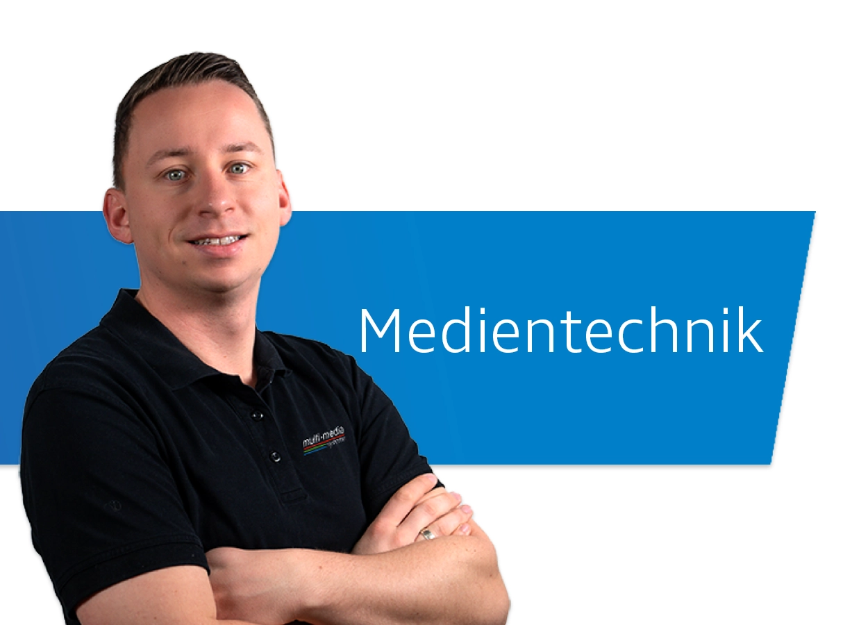 Mitarbeiter der Medientechnik posiert vor dem Schriftzug "Medientechnik"