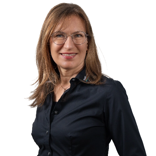 Eine Frau mit langen braunen Haaren, Brille und einem schwarzen Hemd mit Knöpfen lächelt selbstbewusst vor einem schlichten weißen Hintergrund und strahlt dabei Professionalität und Ehrgeiz in ihrer Karriere aus. Eine Frau mit langen braunen Haaren, Brille und einem schwarzen Hemd mit Knöpfen lächelt selbstbewusst vor einem schlichten weißen Hintergrund und strahlt dabei Professionalität und Ehrgeiz in ihrer Karriere aus.