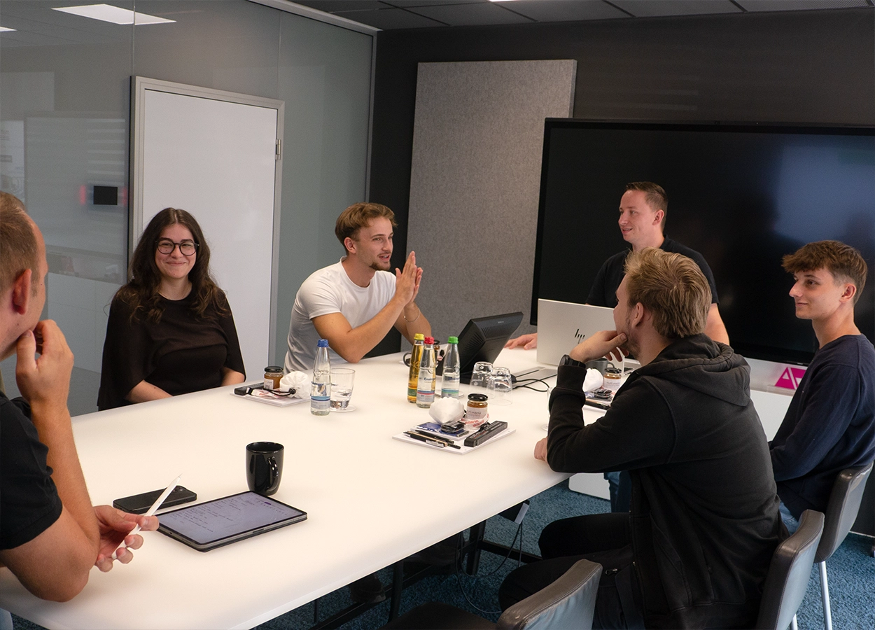 Vier junge Auszubildende sitzen um einen Besprechungstisch